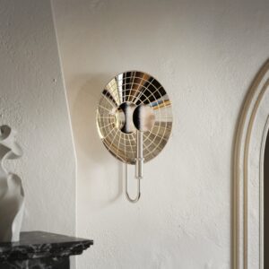 The '54 mirrored wall sconce in old nickel on a white plaster wall beside an arched doorway