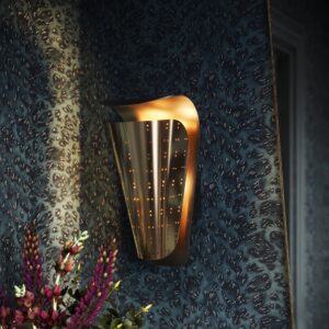 Mirage perforated wall sconce in unlacquered brass on a dark blue patterned wall
