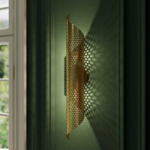 Tangier pierced metal wall sconce in unlacquered brass on a green paneled wall beside a window