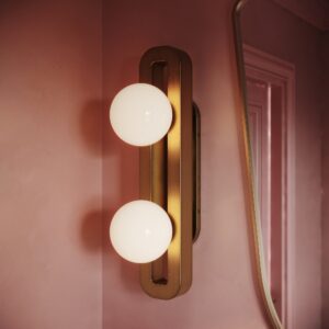 Rio opal globe wall sconce in unlacquered brass on a pink plaster bathroom wall