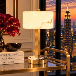 Close-up of the Cortile cordless alabaster table lamp on a brass bar cart, with a city skyline beyond